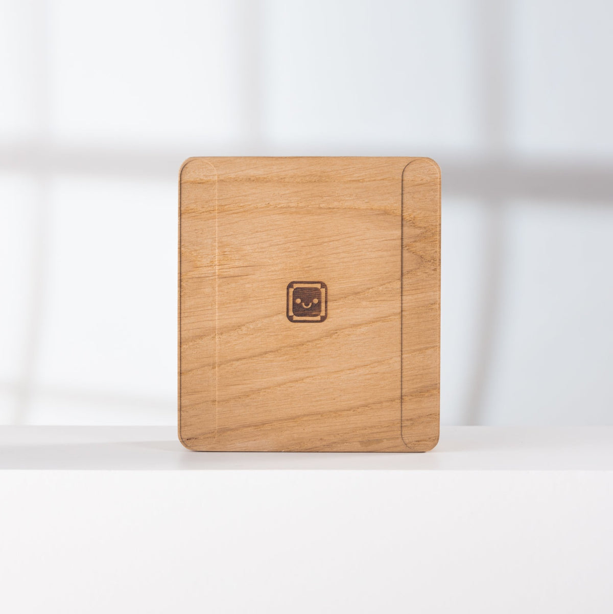 Solid 24” iMac Riser - Oak with all hands on keyboard logo on a white surface